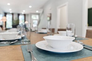 A dining table set with white plates, cutlery, and glasses, with a blue placemat.