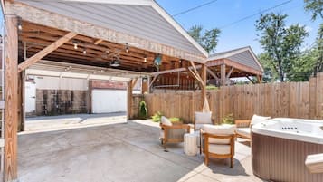 A covered outdoor area with a hot tub, seating, and a garage.