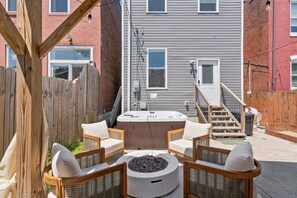 A backyard with a hot tub, outdoor seating, and a fire pit.