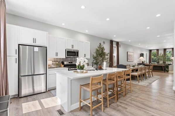 A modern kitchen with white cabinetry, stainless steel appliances, and a central island with seating.