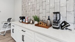 Et køkken med en hvid bordplade, kaffemaskine, blender og brødrister.