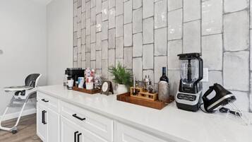 A kitchen with a white countertop, a coffee machine, a blender, and a toaster.
