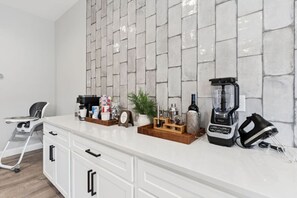 Eine Küche mit weißer Arbeitsplatte, einer Kaffeemaschine, einem Mixer und einem Toaster.