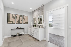 A modern bathroom with a vanity, a mirror, and abstract wall art.