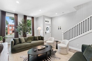 A modern living room with a sofa, chairs, a coffee table, and a staircase. - The Jefferson Social | Sleeps 12 | Pool Table (St. Louis)