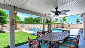 A covered outdoor area with a pool, lounge chairs, and a wooden table. - Desert Retreat with Private Pool & Spa | Near Downtown Palm Springs (Palm Springs)