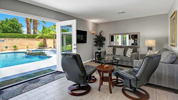 A modern living room with a pool, grey sofas, and a glass coffee table. - Desert Retreat with Private Pool & Spa | Near Downtown Palm Springs (Palm Springs)