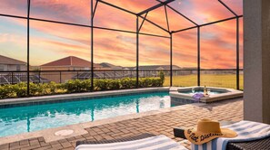A pool area with a hot tub, lounge chairs, and a view of a sunset. - Disney Escape . Family Retreat . Private Pool (Davenport)