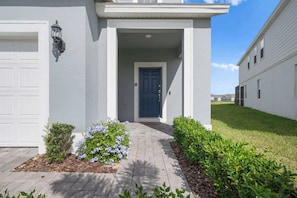 A residential building with a white exterior, a blue door, and a small porch area. - Disney Escape . Family Retreat . Private Pool (Davenport)