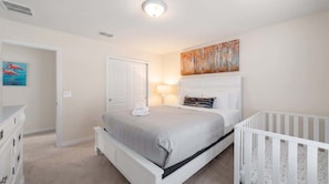 A bedroom with a bed, a crib, a painting, and a door. - Disney Escape . Family Retreat . Private Pool (Davenport)