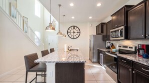A modern kitchen with a central island, dark cabinetry, stainless steel appliances, and pendant lighting. - Disney Escape . Family Retreat . Private Pool (Davenport)