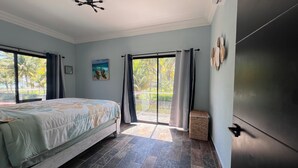 A bedroom with a bed, a ceiling fan, a window with curtains, and a view of the outdoors. - Paradise found on Costa Azul, sleeps 12 in 5 bedrooms. One minute to the beach (Acajutla)