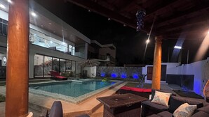 A modern outdoor pool area with lounge seating and a stone wall. - Paradise found on Costa Azul, sleeps 12 in 5 bedrooms. One minute to the beach (Acajutla)