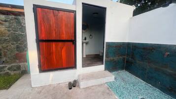 Un petit espace extérieur clos, doté d’une porte en bois, d’un sol carrelé et d’un mur recouvert de carreaux bleus.