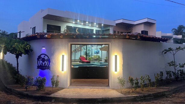 A modern hotel with a swimming pool, a well-lit entrance, and a clear view of the pool area. - Paradise found on Costa Azul, sleeps 12 in 5 bedrooms. One minute to the beach (Acajutla)