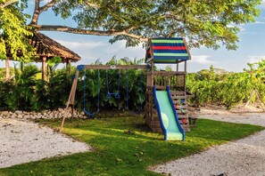 Une aire de jeux avec un toboggan, des balançoires et une structure d’escalade.