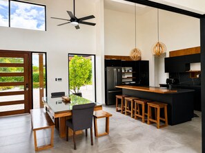 Une cuisine moderne avec un îlot central, des appareils électroménagers noirs et des tabourets de bar en bois.