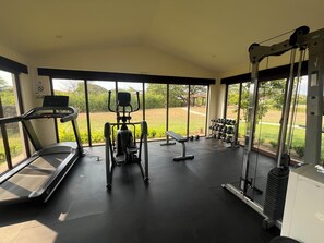 Une salle de sport équipée de tapis de course, d’appareils de musculation et d’haltères.