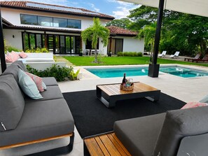 A modern outdoor living area with a pool, a sofa set, and a dining table. - 4-Bedroom House with Pool at Hacienda Pinilla (Pinilla)