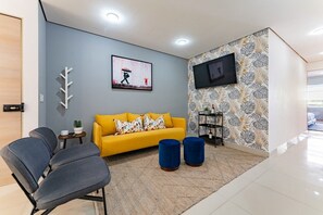 A modern living room with a sofa, chairs, a TV, and a patterned wall. - Stylish 3BR Stay • Roma Norte, Balcony & Workspace (Ciudad de México)