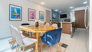 Eine moderne Küche mit Einbauofen, Kühlschrank und Essbereich mit Glastisch und Stühlen.