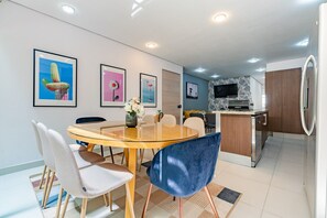 A modern kitchen with a built-in oven, a refrigerator, and a dining area with a glass table and chairs. - Stylish 3BR Stay • Roma Norte, Balcony & Workspace (Ciudad de México)