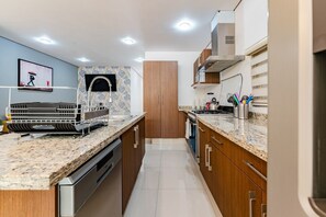 A modern kitchen with granite countertops, stainless steel appliances, and wooden cabinets. - Stylish 3BR Stay • Roma Norte, Balcony & Workspace (Ciudad de México)