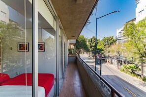 Ein Balkon mit Blick auf eine Straße, eine rote Bank und ein Geländer.