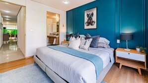 Ein modernes Schlafzimmer mit einem großen Bett, einem Nachttisch mit Lampe und einem an der Wand hängenden Kunstwerk.
