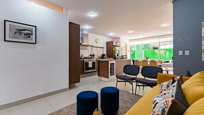 Ein modernes Wohnzimmer mit einer Couch, Hocker und einem Essbereich mit Stühlen und einem Tisch.