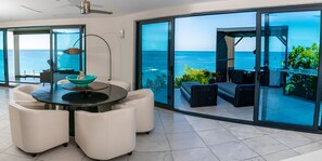 Una sala moderna con un gran ventanal que da a un balcón con vistas al mar.