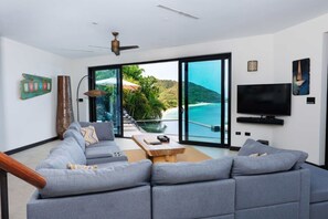 Ein modernes Wohnzimmer mit einem grauen Sofa, einem Holztisch und einem Fernseher.