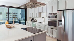 A modern kitchen with a central island, stainless steel appliances, and a view through a glass door. - A Memorable Stay Awaits You Here! Villa Overlooking the Caribbean Sea! (Urlings)