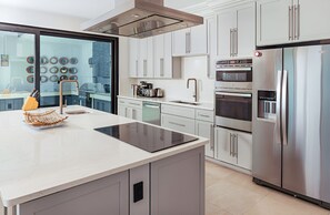 A modern kitchen with a central island, stainless steel appliances, and a view through a glass door. - A Memorable Stay Awaits You Here! Villa Overlooking the Caribbean Sea! (Urlings)