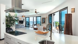 A modern kitchen with a large island, a built-in stove, and a large window overlooking the ocean. - A Memorable Stay Awaits You Here! Villa Overlooking the Caribbean Sea! (Urlings)