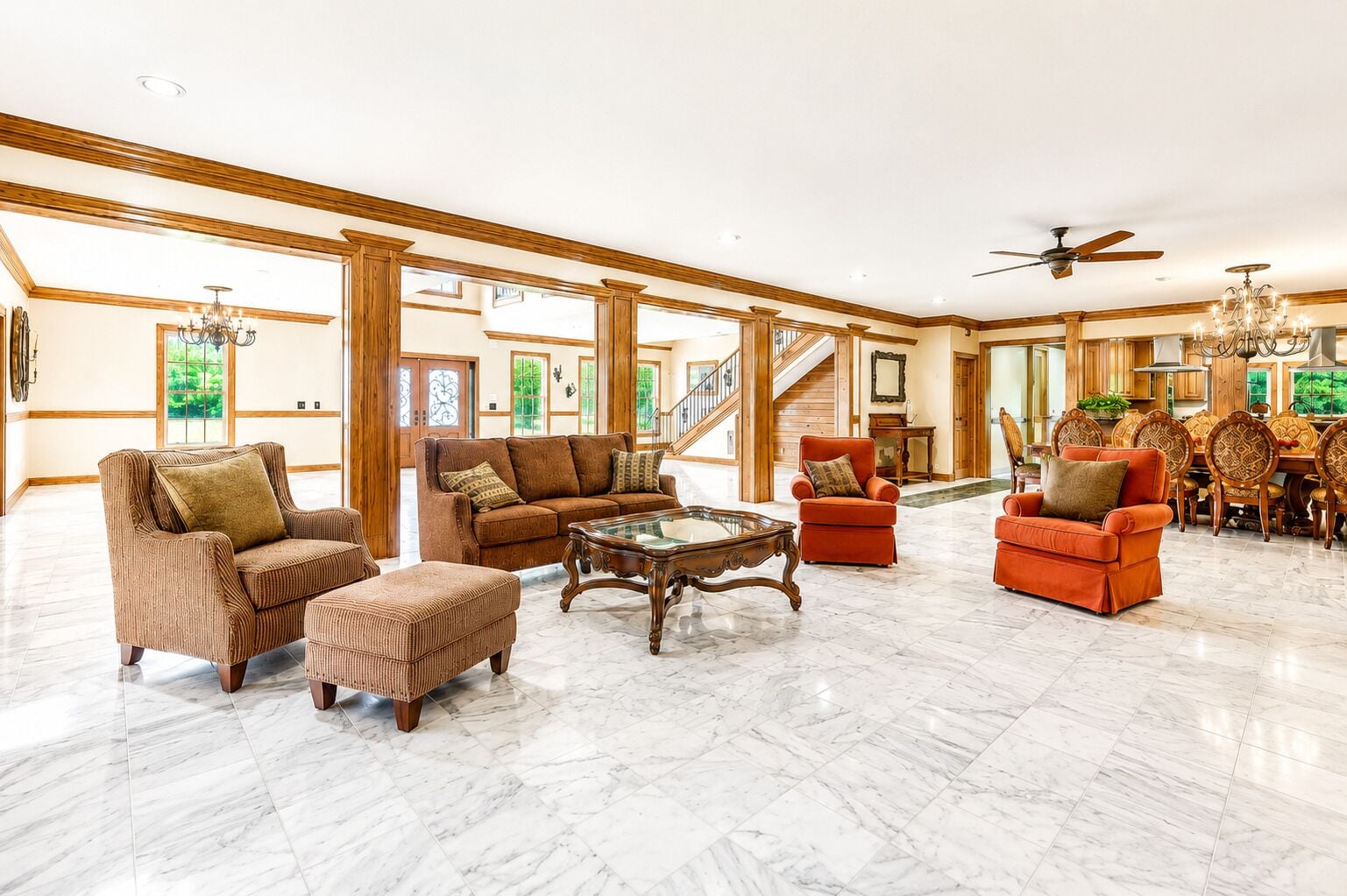 A spacious living area with a high ceiling, a marble floor, and a staircase leading to an upper level.