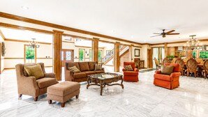 A spacious living area with a high ceiling, a marble floor, and a staircase leading to an upper level.