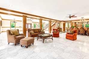A spacious living area with a high ceiling, a marble floor, and a staircase leading to an upper level.