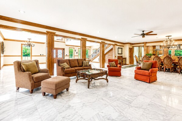 A spacious living area with a high ceiling, a marble floor, and a staircase leading to an upper level.