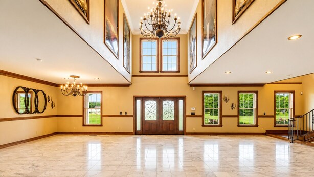 A spacious hall with a high ceiling, large windows, and a grand chandelier.