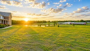 A large grassy field with a building on the left and a barn on the right.