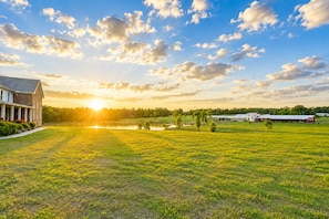 A large grassy field with a building on the left and a barn on the right.