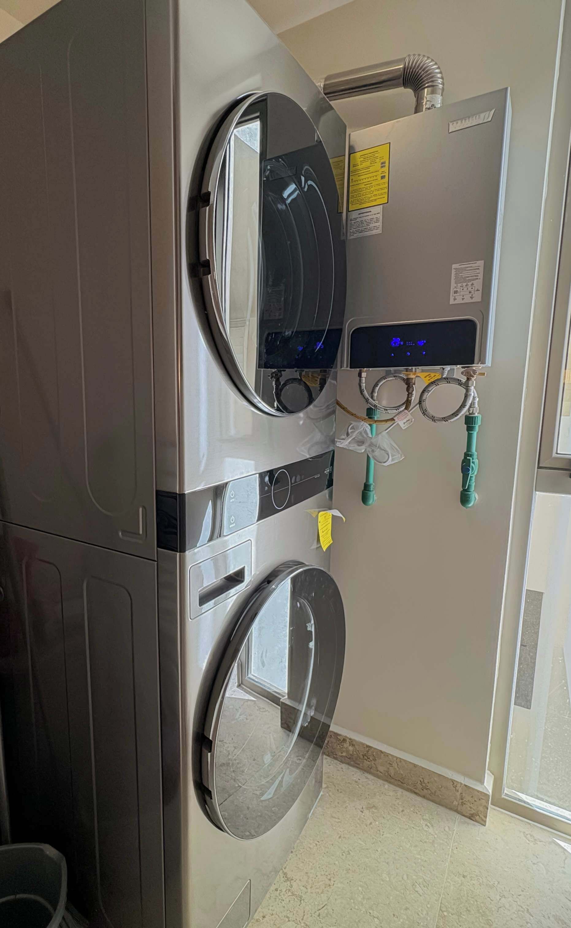 Una lavadora grande y moderna con dos tambores, un panel de control con pantallas digitales y una manguera de entrada de agua.