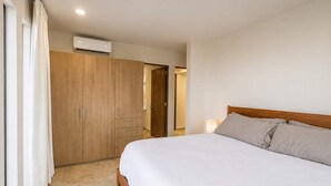Quarto com cama, guarda-roupa e ar condicionado.