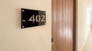 Placa preta com o número 402 em uma parede bege.