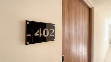 A black number plate with the number 402 on a beige wall.