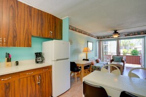 Eine kompakte Küche mit Holzschränken, einem weißen Kühlschrank und einem Essbereich mit Tisch und Stühlen.