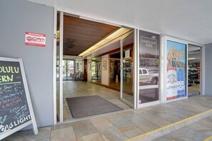 Een gevel met een bord voor een lokale pub, een waarschuwingsbord voor beveiliging en een Budweiser reclame.