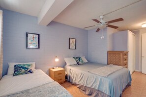 A bedroom with two beds, a ceiling fan, and artwork on the walls. - Hawaiian King: Spacious 1-bedroom apt in central Waikiki, 0.3ml to beach, Pool (Honolulu)