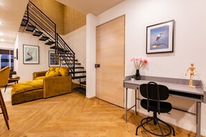 A modern living space with a staircase, a sofa, a desk, and a chair. - 3BR Roma Norte Penthouse w/ Private Rooftop (Ciudad de México)
